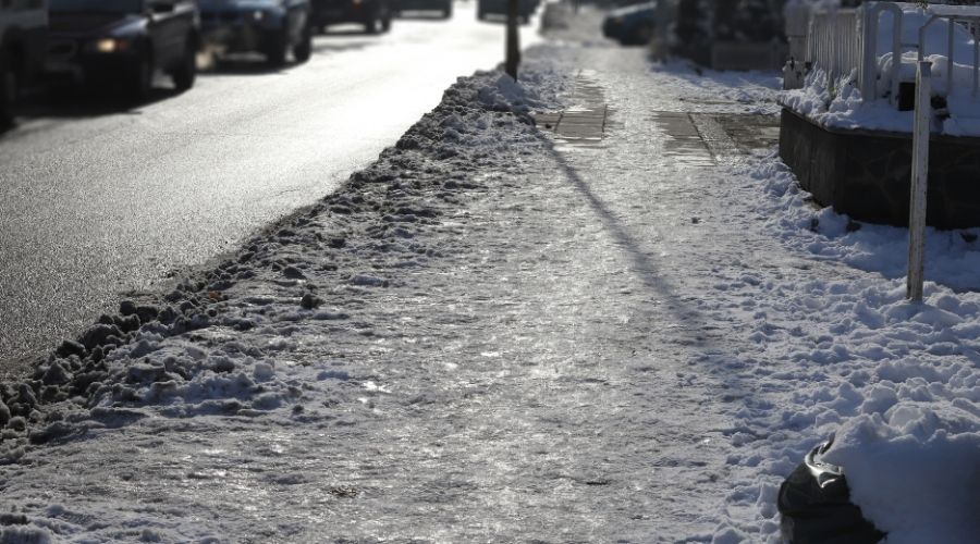 Ice covers a well-used sidewalk in a residential area.