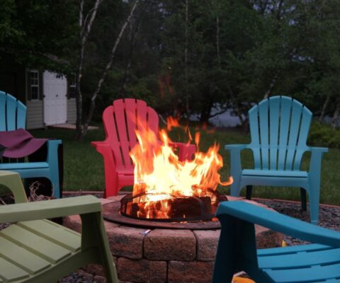 Plastic chairs around a fire pit with a glowing fire.